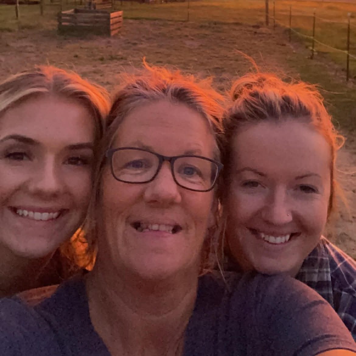 Three women pose for a selfie at sunset